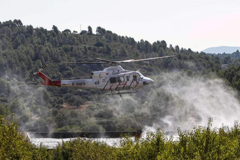 Un helicÃ³ptero carga agua para dirigirse al frente del incendio declarado en Les Useres a mediados de agosto. EFE/DomÃ©nech CastellÃ³/Archivo
