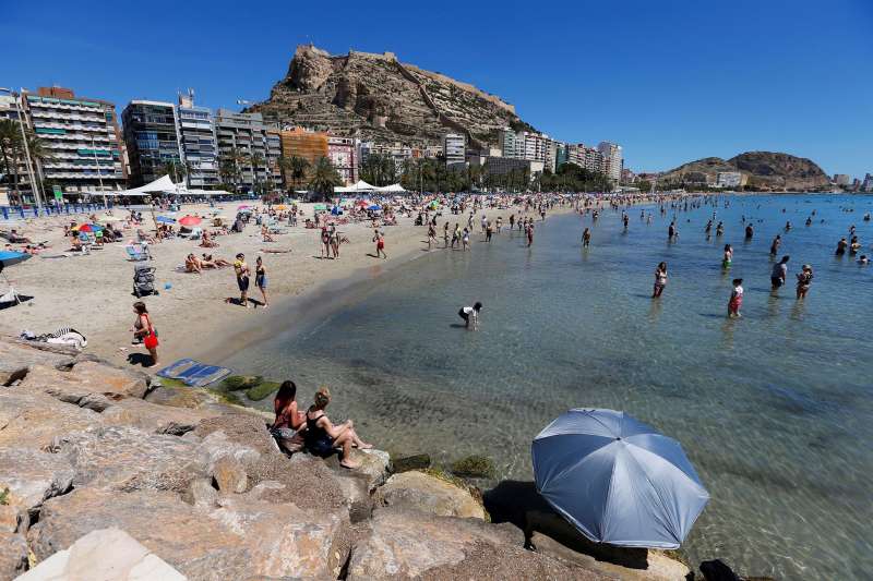 Bañistas disfrutan de un día de sol en la playa del Postiguet en Alicante.