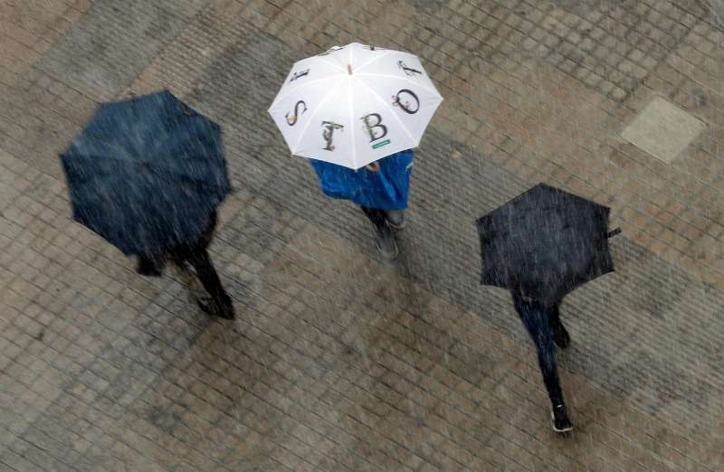 Varias personas se protegen de la lluvia con paraguas. EFE