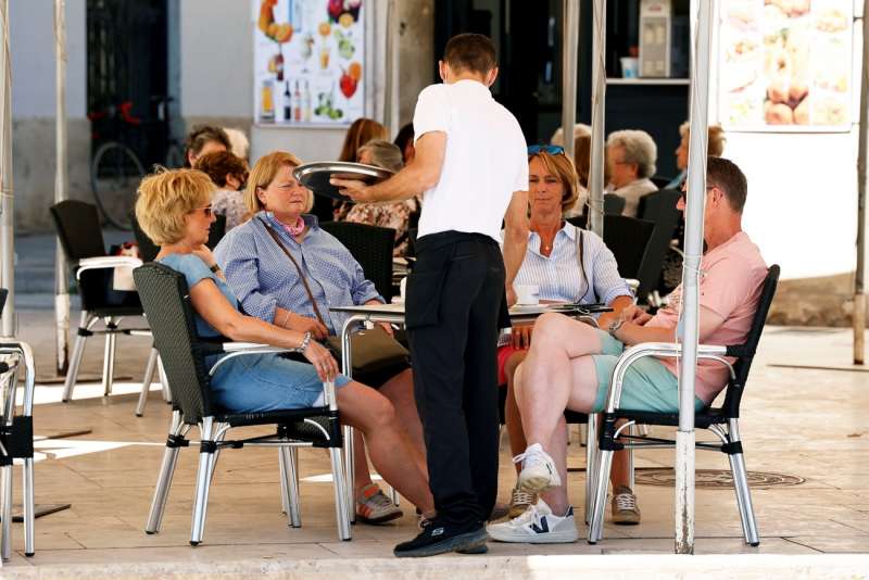 Varios turistas son atendidos por un camarero en València. EFE/Biel Aliño/Archivo
