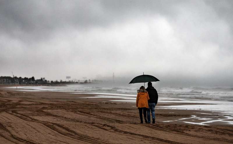 En la imagen, una pareja pasea por la playa en un día de lluvia. EFE/ Manuel Bruque/Archivo